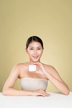 Ardent woman smiling holding mockup product for advertising text place, light grey background. Concept of healthcare for skin, beauty care product for advertising.