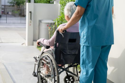 Caregiver help and care Asian senior or elderly old lady woman patient sitting in wheelchair on ramp at nursing hospital, healthy strong medical concept