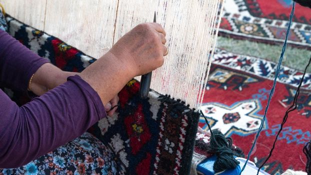 Grandma weaves a carpet on a loom of thread, making a rug. High quality photo