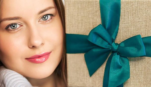 Winter holidays, present and Merry Christmas concept, happy woman smiling and holding wrapped gift box, close-up portrait