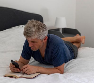 Shot of a mid aged man laying on the bed and reading book