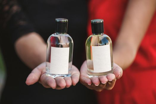 Perfume bottle of a female hand. Young stylish woman holding a bottle of perfume. Fashionable perfume in the hands of women. Girl spraying perfume. Beautiful female hands. Perfumes for women