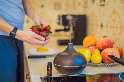 A man prepares food next to an aroma diffuser. cook cuts ripe red peppers in the kitchen. Cooking fresh, ripe, bell pepper salad for guests. Summer fresh vegetable salad.