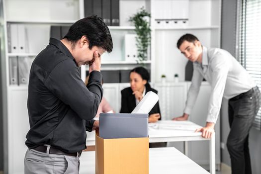 Depressed and disappointed employee packing his belongings after being fired for not being competent. Gossiped by his colleagues behind his back. Layoff due to economic depression.