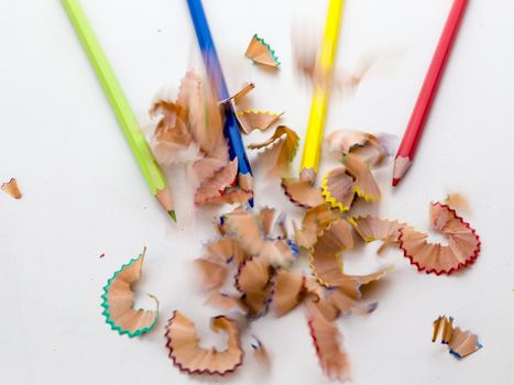 Colored pencil crayons in a row with shavings on white background