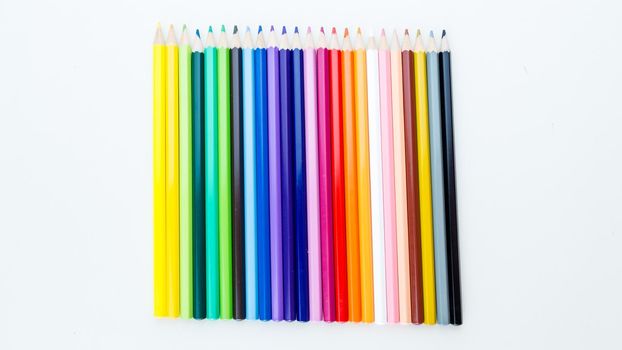 Colored pencil crayons in a row on white background