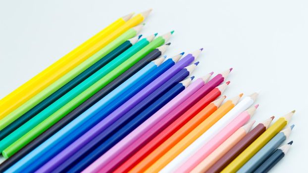 Colored pencil crayons in a row on white background