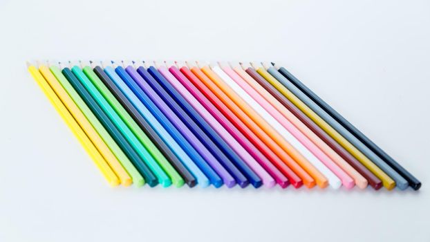 Colored pencil crayons in a row on white background