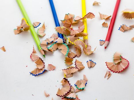 Colored pencil crayons in a row with shavings on white background