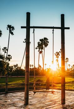 silhouette Empty swings at sunset time on tropical landscape background.