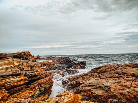 rocky coastline with ocean waves splashing on shore nature landscape background.