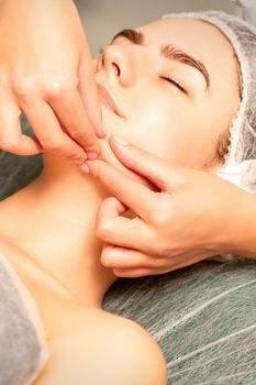 Beautiful young caucasian woman with closed eyes receiving a facial massage in a beauty salon