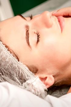 Facial massage. Hands of a masseur massaging neck of a young caucasian woman in a spa salon, the concept of health massage