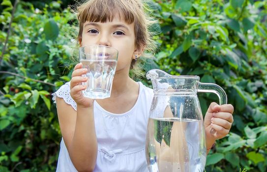 The child drinks clean water in summer. Selective focus. People.