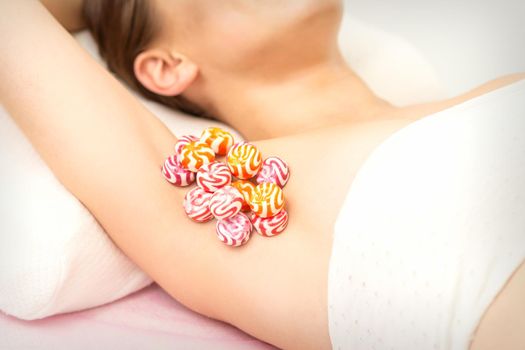 Waxing, depilation armpit concept. Colored round candies lying down on the female armpit, close up