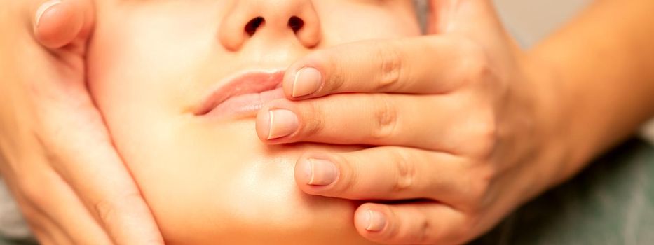 Beautiful young caucasian woman with closed eyes receiving a facial massage in a beauty salon