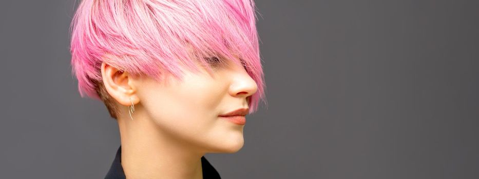 Profile of a beautiful young caucasian woman with short straight bob hairstyle dyed in pink color with closed eyes with copy space