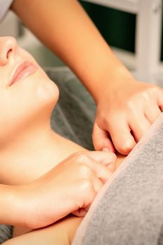 Massaging female breast, and shoulder. Young beautiful caucasian woman receiving chest and shoulders massage in beauty spa salon