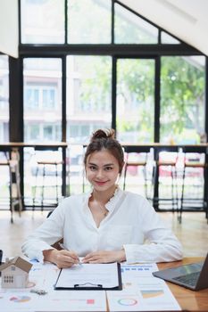 Portrait of a beautiful bank young woman sign credit department of signing approval for a home loan.