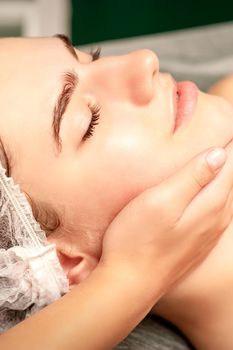 Facial massage. Hands of a masseur massaging neck of a young caucasian woman in a spa salon, the concept of health massage