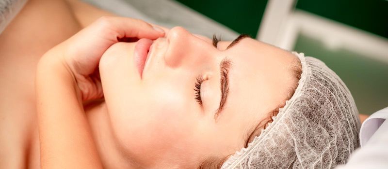 Facial massage. Hands of a masseur massaging neck of a young caucasian woman in a spa salon, the concept of health massage