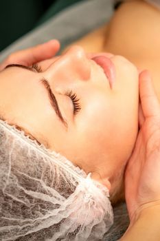 Facial massage. Hands of a masseur massaging neck of a young caucasian woman in a spa salon, the concept of health massage