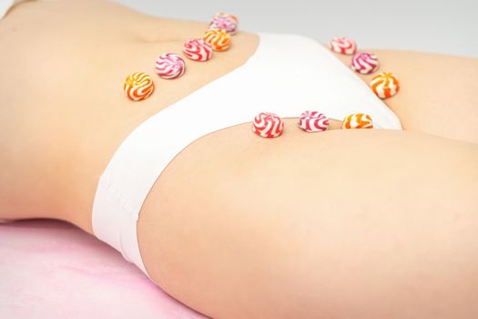 Concept of intimate depilation, intimate waxing, depilation. Round candies lying down in a row on the female bikini zone, intimate area, close up