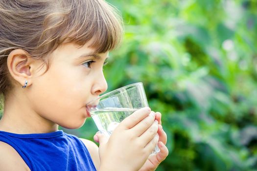 The child drinks clean water in summer. Selective focus. People.