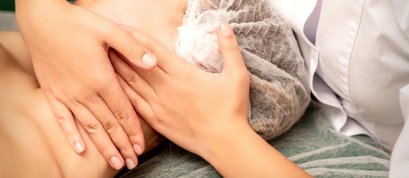 Facial massage. Hands of a masseur massaging neck of a young caucasian woman in a spa salon, the concept of health massage