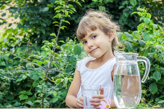 The child drinks clean water in summer. Selective focus. People.