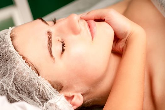 Facial massage. Hands of a masseur massaging neck of a young caucasian woman in a spa salon, the concept of health massage