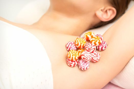 Waxing, depilation armpit concept. Colored round candies lying down on the female armpit, close up