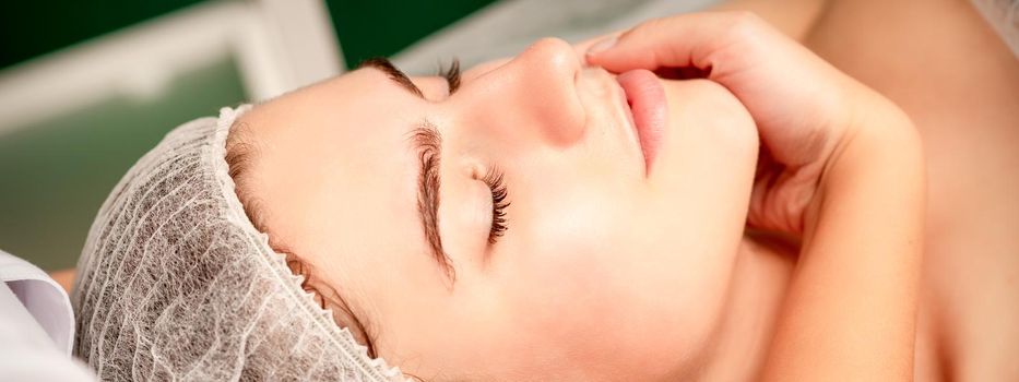 Facial massage. Hands of a masseur massaging neck of a young caucasian woman in a spa salon, the concept of health massage