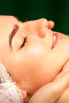 Facial massage. Hands of a masseur massaging neck of a young caucasian woman in a spa salon, the concept of health massage