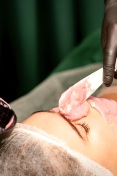 Beautiful young caucasian woman receiving an alginic mask to the face in beauty salon. Facial skin treatment