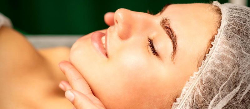 Facial massage. Hands of a masseur massaging neck of a young caucasian woman in a spa salon, the concept of health massage