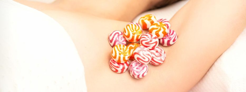 Waxing, depilation armpit concept. Colored round candies lying down on the female armpit, close up