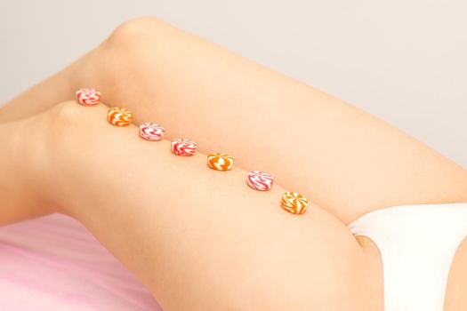 Depilation, waxing concept. Round candies lying down in a row on the female leg, close up