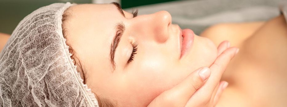 Facial massage. Hands of a masseur massaging neck of a young caucasian woman in a spa salon, the concept of health massage