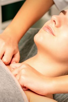 Massaging female breast, and shoulder. Young beautiful caucasian woman receiving chest and shoulders massage in beauty spa salon