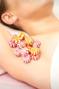 Waxing, depilation armpit concept. Colored round candies lying down on the female armpit, close up