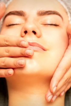 Beautiful young caucasian woman with closed eyes receiving a facial massage in a beauty salon