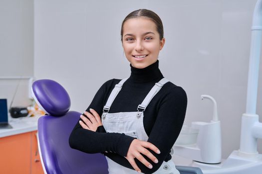 Portrait of young smiling teenage girl in dental chair looking at camera. Teenage female patient in dentist office. Adolescence, hygiene, treatment, dental health care