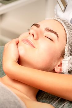 Facial massage. Hands of a masseur massaging neck of a young caucasian woman in a spa salon, the concept of health massage