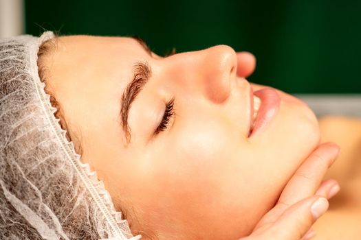 Facial massage. Hands of a masseur massaging neck of a young caucasian woman in a spa salon, the concept of health massage