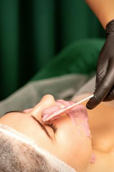 Beautiful young caucasian woman receiving an alginic mask to the face in beauty salon. Facial skin treatment