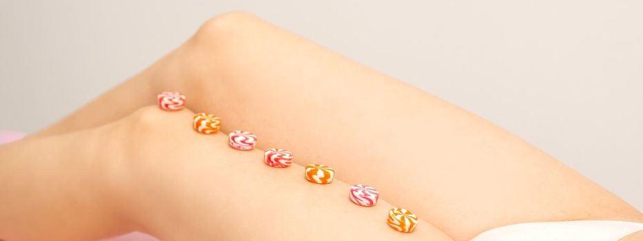 Depilation, waxing concept. Round candies lying down in a row on the female leg, close up