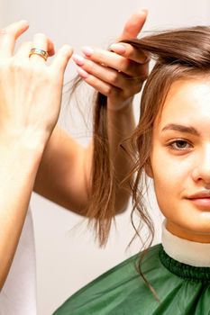 Hairstyling bride. A female hairdresser makes styling hair for the beautiful young caucasian woman in a beauty salon