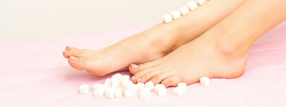 The concept of epilation, waxing. Sugar cubes lie down in a row on the naked white female leg