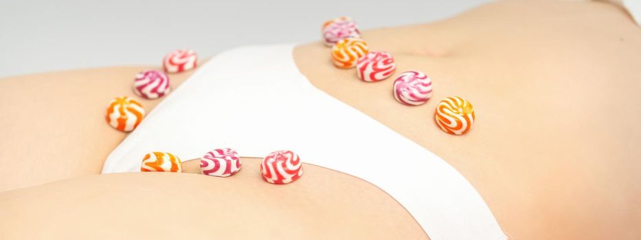 Concept of intimate depilation, intimate waxing, depilation. Round candies lying down in a row on the female bikini zone, intimate area, close up